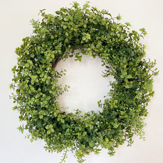 Artificial boxwood and small green berries on a grapevine base